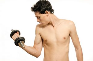Skinny man training his bicep muscle. Beautiful teenager lifting dumbbell